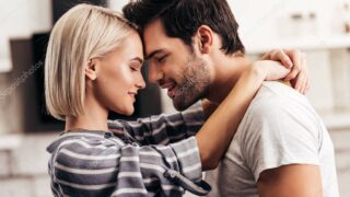 handsome boyfriend and attractive girlfriend hugging and smiling in kitchen